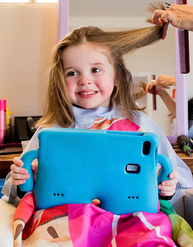criança no salão durante corte de cabelo infantil tranquilo com o profissional