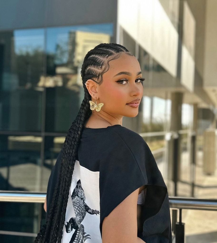 Mulher com tranças afro em cabelo cacheado e elástico delicado, visual elegante e versátil