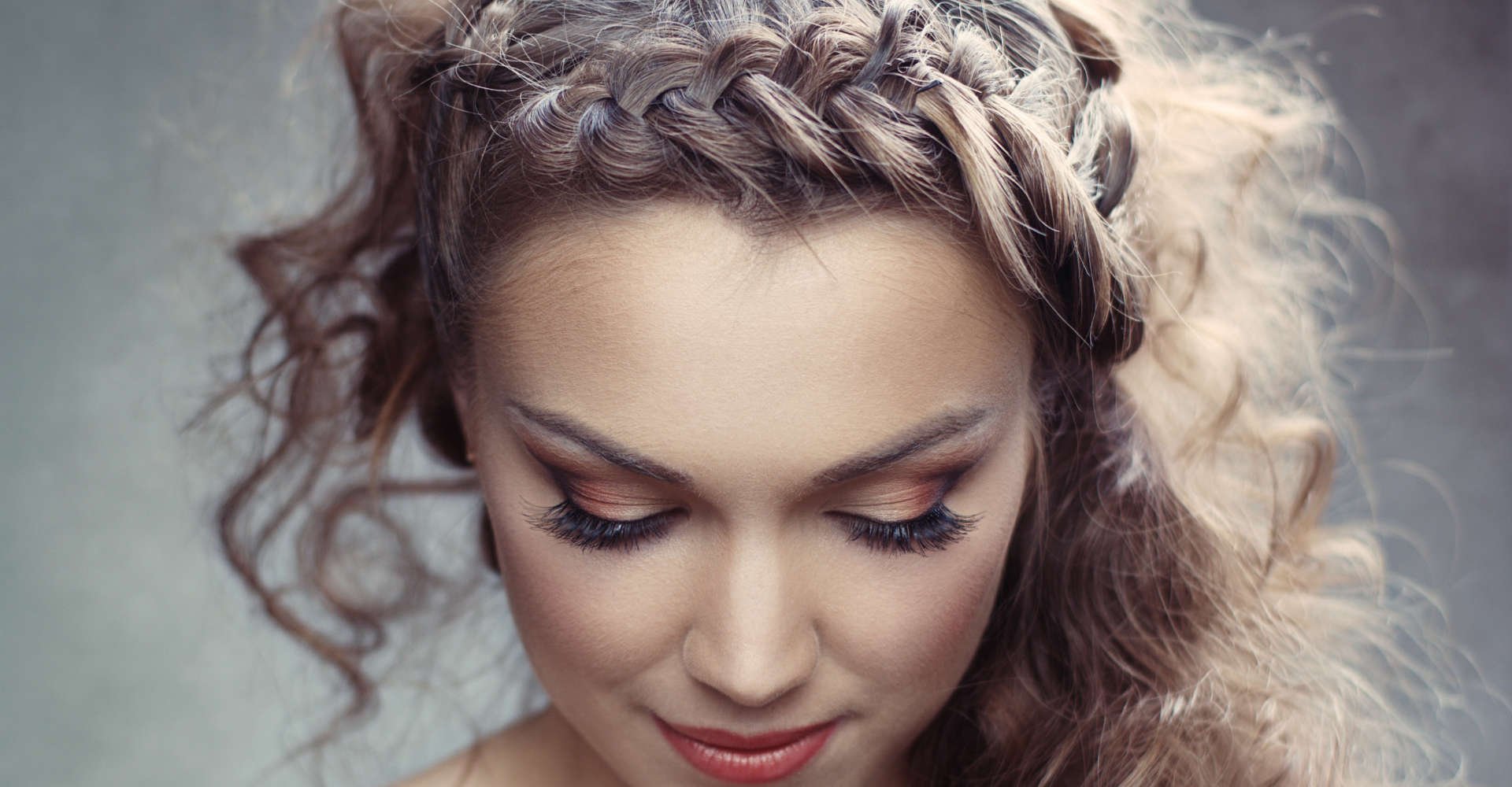 Mulher com cabelo cacheado meio preso, tranças laterais e presilhas decorativas