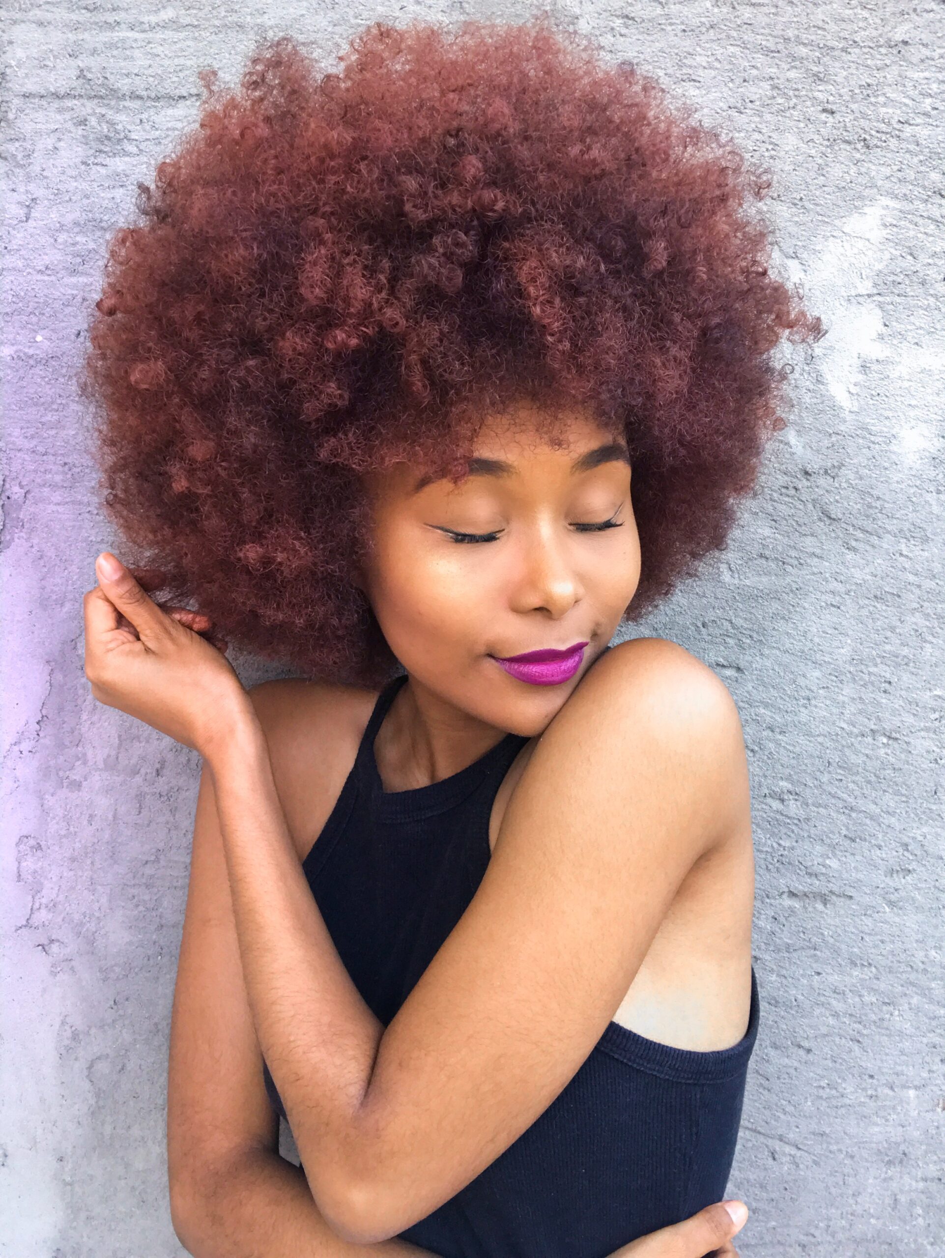 Mulher com cabelo crespo colorido recebendo cuidado especializado de coloração