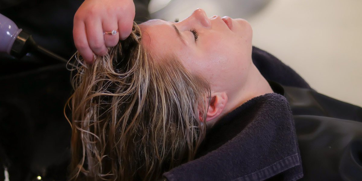 Mulher aplicando máscara de reconstrução capilar em cabelo recém colorido