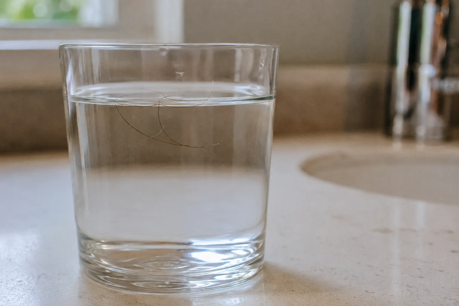 Copo transparente com água e fio de cabelo para teste de porosidade