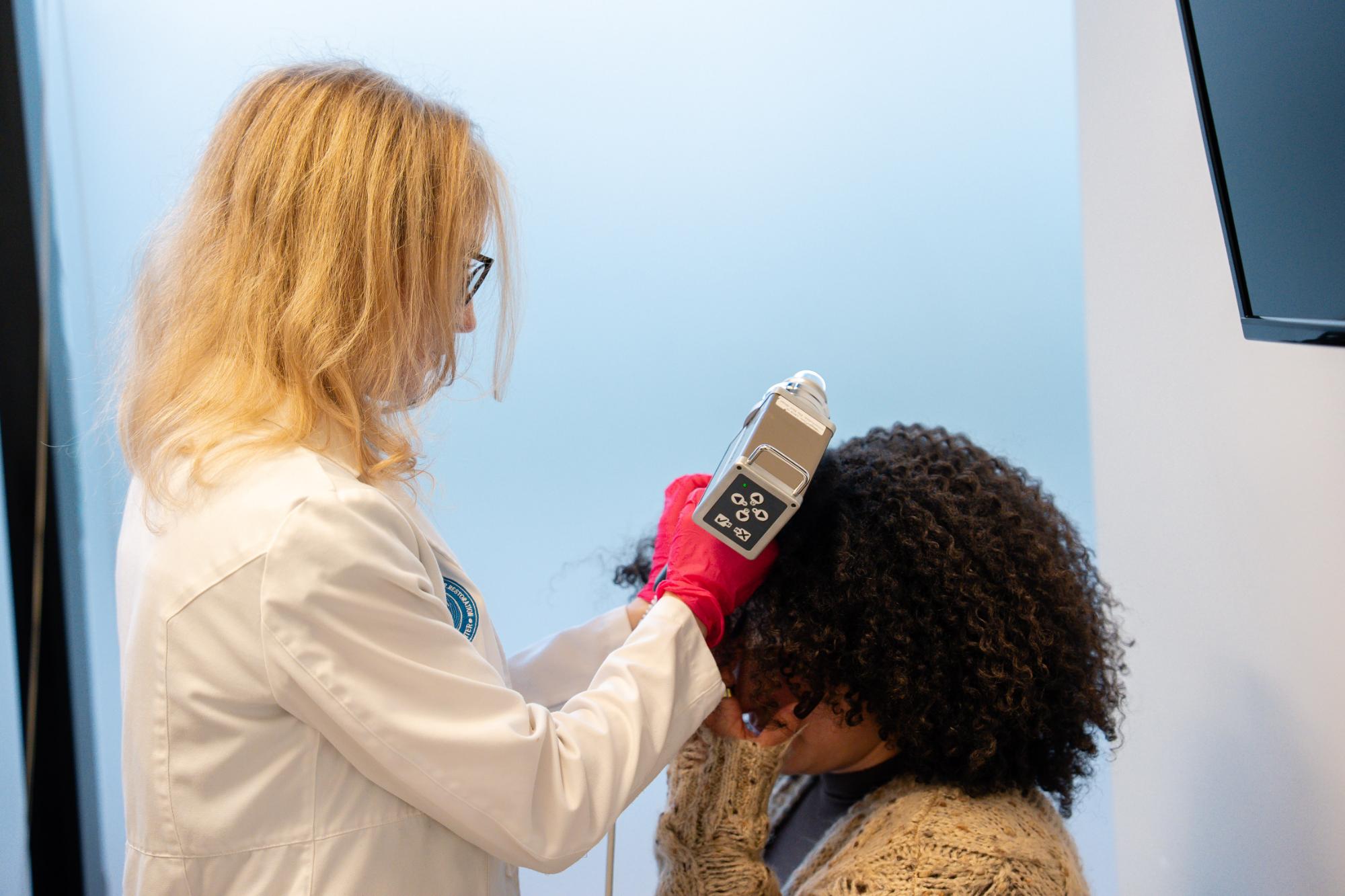 Dermatologista analisando fio de cabelo em consulta profissional