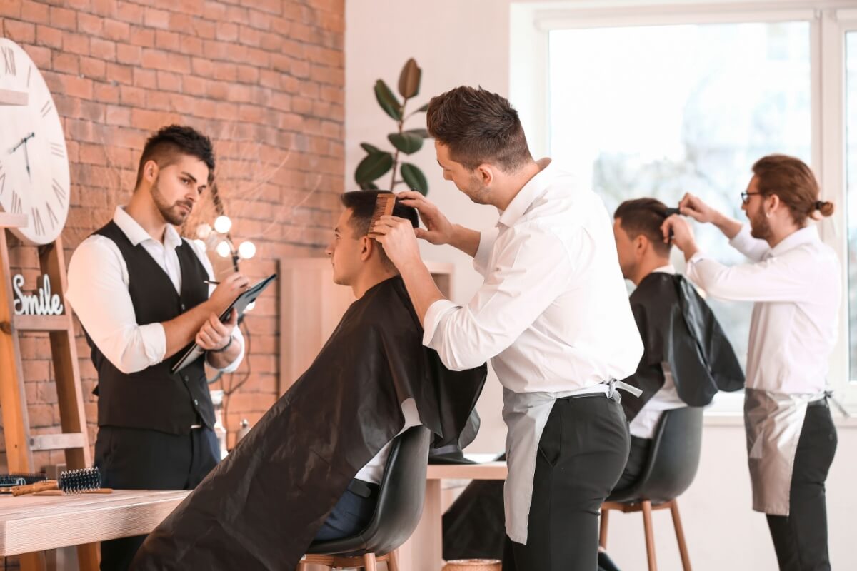 Barbeiro fazendo degradê em cabelo masculino, exemplo de nomes de penteados masculinos