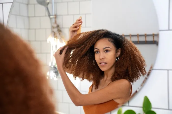 Mulher aplicando shampoo no couro cabeludo antes do condicionador, seguindo a ordem correta de lavar o cabelo