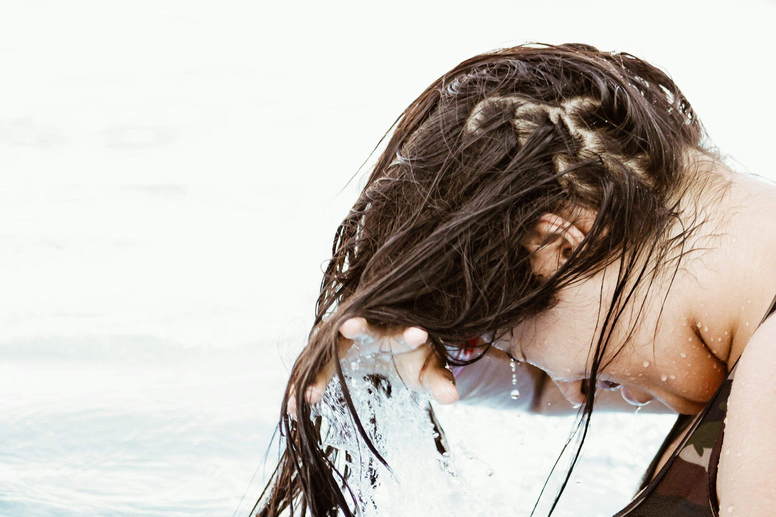 Homem enxaguando o cabelo com água doce depois de um dia de praia
