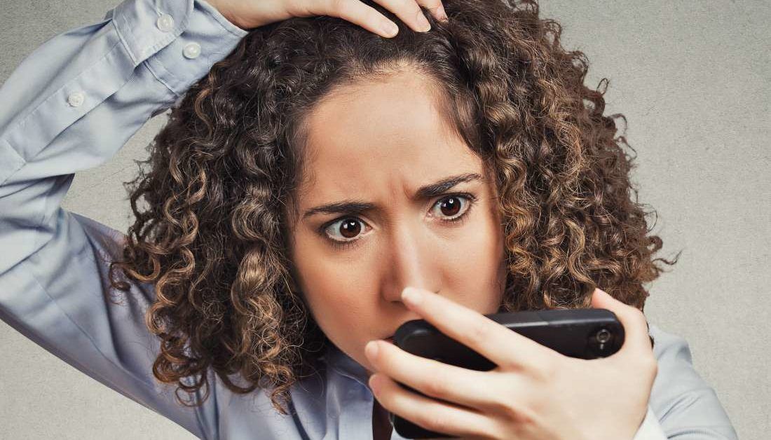 Mulher comparando fotos antigas no celular para observar a linha do cabelo